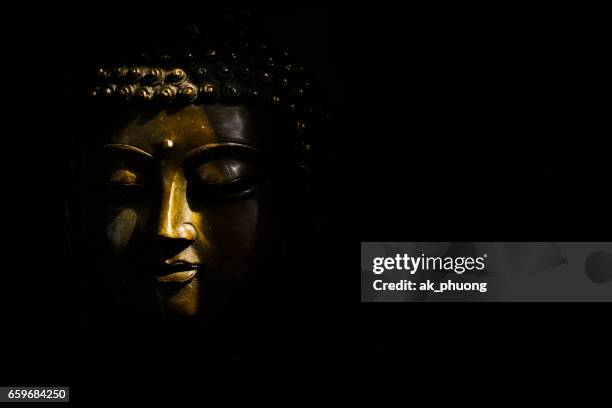 sunlight on buddha face against with black background - buddha face stockfoto's en -beelden