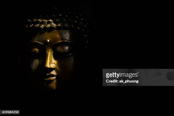 sunlight on buddha face against with black background - buddha face stock pictures, royalty-free photos & images