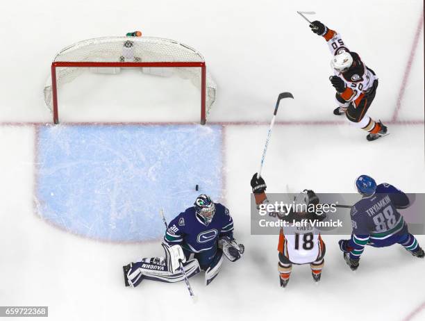 Ryan Miller and Nikita Tryamkin of the Vancouver Canucks look on as Antoine Vermette celebrates the goal of Patrick Eaves of the Anaheim Ducks during...