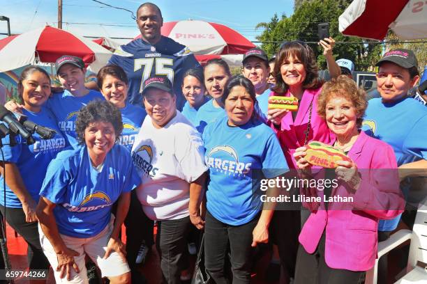 Tackle Chris Hairston, Pink's Co-Owner Gloria Pink and Co-Owner Beverly Pink-Wolfe pose with Pink's Hot Dogs staff at the unveiling of the "Chargers...