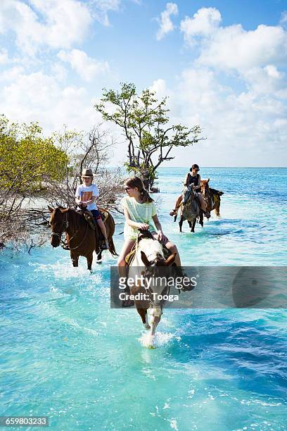 Family riding horses through water