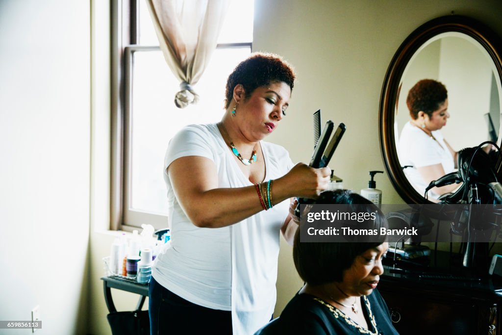 Salon owner straightening hair of client in salon