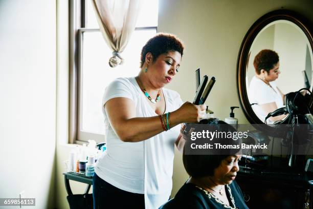 salon owner straightening hair of client in salon - black hair bildbanksfoton och bilder