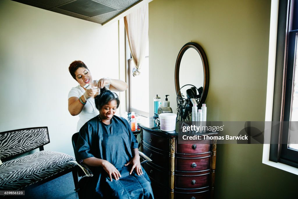 Salon owner straightening clients hair in salon