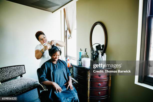 salon owner straightening clients hair in salon - black hair salon stock pictures, royalty-free photos & images