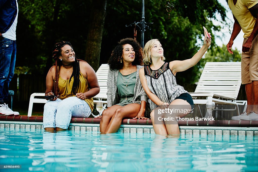 Smiling friends taking selfie with smartphone