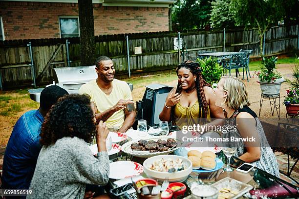 laughing friends dining in backyard - daytime activities stock pictures, royalty-free photos & images