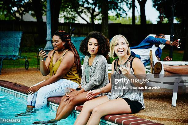 smiling women sitting on edge of pool during party - summer cardigan women stockfoto's en -beelden