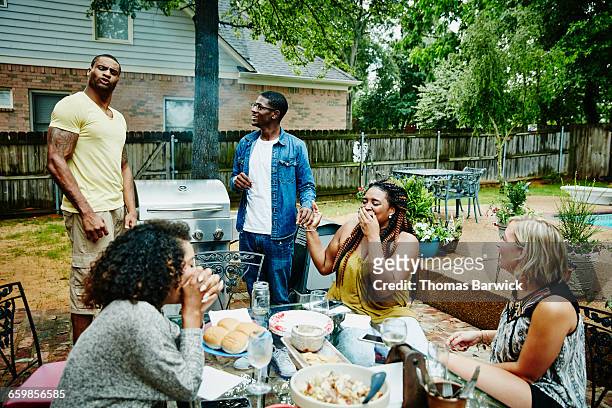 laughing group of friends barbecuing in backyard - grill party stock pictures, royalty-free photos & images