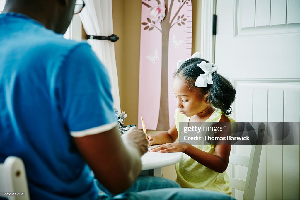 Young girl drawing with father at table