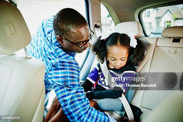 father buckling daughter into car seat in car - guy in car seat stockfoto's en -beelden