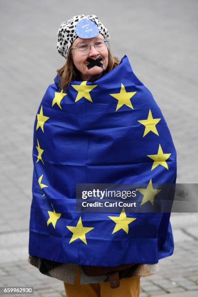 Protester with her mouth taped up wears a European Union flag as she takes part in a demonstration near parliament on March 29, 2017 in London,...