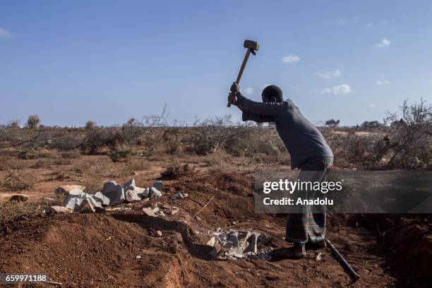 Somalian man breaks stones before to build a tent at the Mooro Hagar camp in the Somalia's Bay state on March 29, 2017. In the central and south...