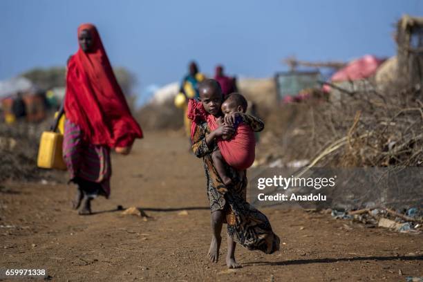 Somalian girl carries her sibling at the Mooro Hagar camp in the Somalia's Bay state on March 29, 2017. In the central and south parts of Somalia,...