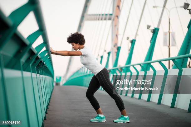 athletic, young woman exercising on city bridge - stretching stock pictures, royalty-free photos & images
