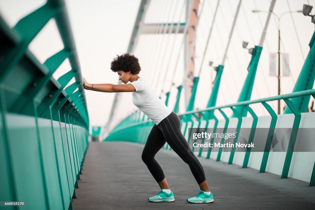 Athletic, young woman exercising on city bridge