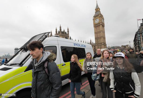 Tourists walk past a police vehicle as emergency services look for a person thought to have fallen from Westminster Bridge into the River Thames on...