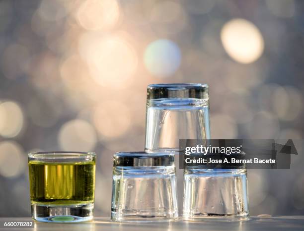 glasses of crystal of chupito one full and another emptiness  , illuminated by the light of the sun - fiesta al aire libre stock pictures, royalty-free photos & images