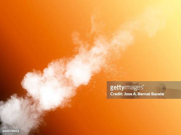 explosion of a cloud of powder of particles of  color white  on yellow and orange  background - orange powder ストックフォトと画像