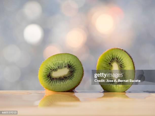 kiwi fruit,  divide  for the half, illuminated by the light of the sun - corte transversal stock-fotos und bilder