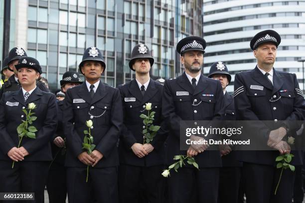 Police officers hold flowers on Westminster Bridge during a vigil to remember the victims of last week's Westminster terrorist attack on March 29,...