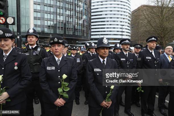 Police officers hold white roses on Westminster Bridge during a vigil to remember the victims of last week's Westminster terrorist attack on March...