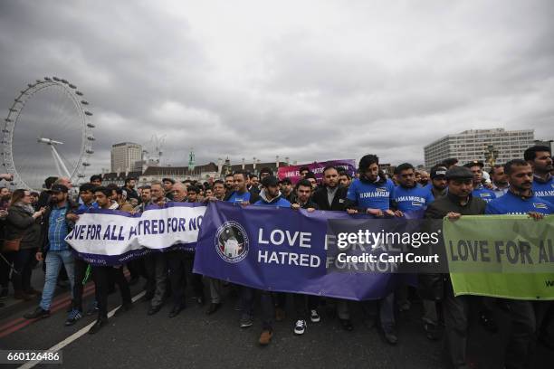People wearing #IAMAMUSLM t-shirts hold a banner reading 'Love for all, hatred for none' on Westminster Bridge as they attend a vigil to remember the...