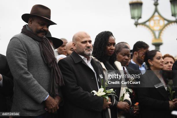 People hold roses on Westminster Bridge as they attend a vigil to remember the victims of last week's Westminster terrorist attack on March 29, 2017...