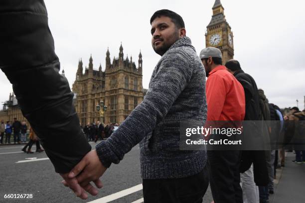 People hold hands on Westminster Bridge as they attend a vigil to remember the victims of last week's Westminster terrorist attack on March 29, 2017...