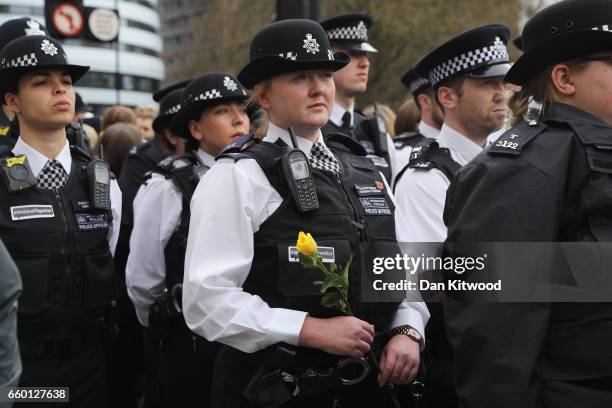 Police officers hold white roses on Westminster Bridge during a vigil to remember the victims of last week's Westminster terrorist attack on March...