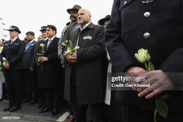 People hold roses on Westminster Bridge as they attend a vigil to remember the victims of last week's Westminster terrorist attack on March 29, 2017...