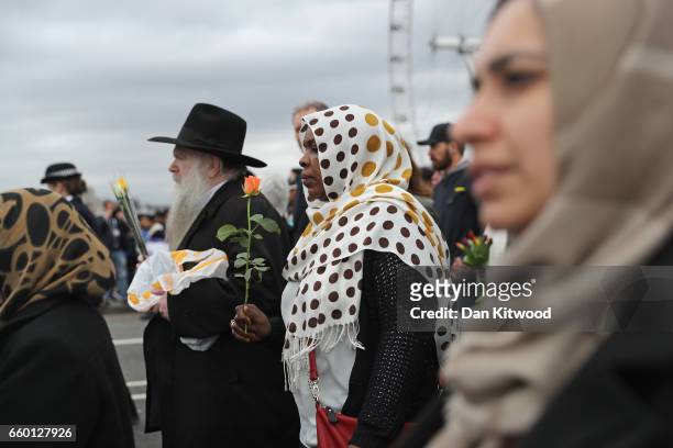 People hold flowers on Westminster Bridge as they attend a vigil to remember the victims of last week's Westminster terrorist attack on March 29,...