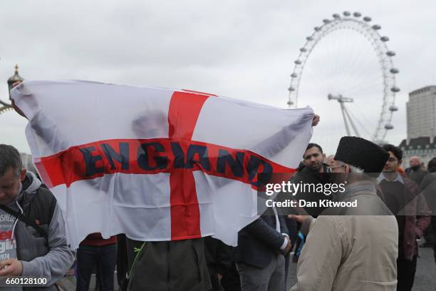 Man holds a St George's Cross flag with 'England' written on it on Westminster Bridge as people attend a vigil to remember the victims of last week's...