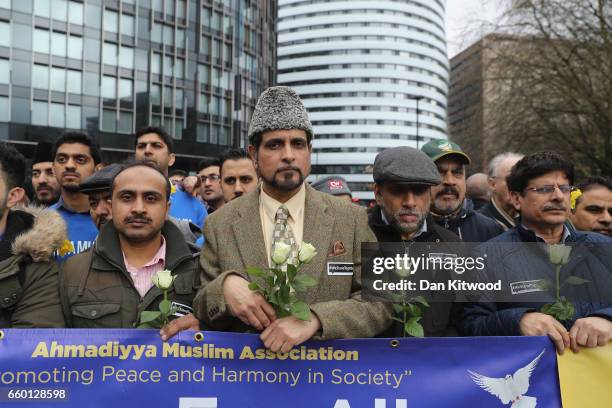 People hold white roses and a banner reading 'Love for all, hatred for none' on Westminster Bridge as they attend a vigil to remember the victims of...