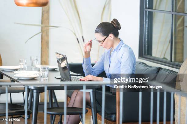 schöne brünette geschäftsfrau auf mittagspause, arbeiten am laptop im restaurant. sie trägt brille - brunette sitting at desk stock-fotos und bilder