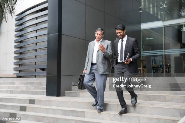 senior businessman an young male colleague leaving offices - walking business man outside stock pictures, royalty-free photos & images