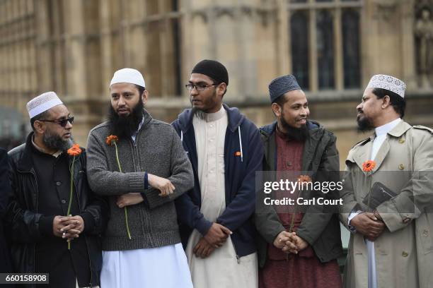Imams hold flowers as they gather on Westminster Bridge ahead of a vigil to remember the victims of last week's Westminster terrorist attack on March...