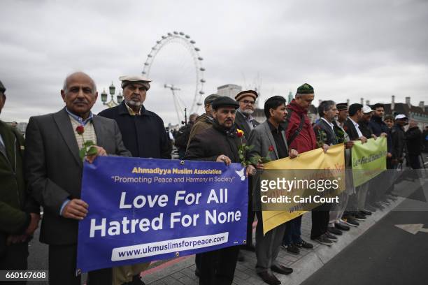 People hold a banner reading 'Love for all, hatred for none' on Westminster Bridge as they attend a vigil to remember the victims of last week's...