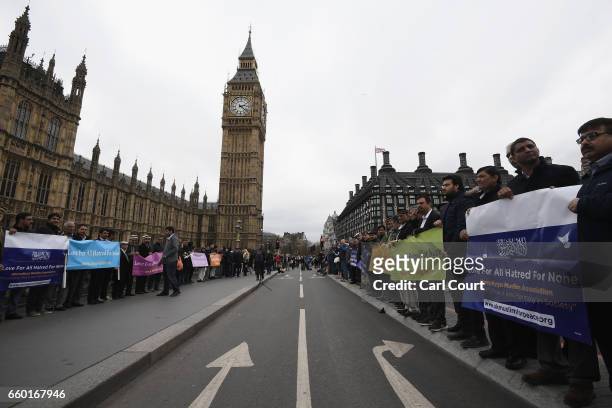 People hold banners reading 'Love for all, hatred for none' on Westminster Bridge as they attend a vigil to remember the victims of last week's...