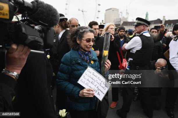 Member of the public carries a single rose and note on Westminster Bridge during a vigil to remember the victims of last week's Westminster terrorist...