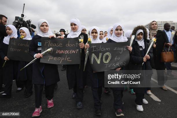 Children hold banners as they walk over Westminster Bridge during a vigil to remember the victims of last week's Westminster terrorist attack on...
