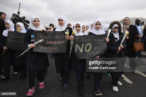 Children hold banners as they walk over Westminster Bridge during a vigil to remember the victims of last week's Westminster terrorist attack on...