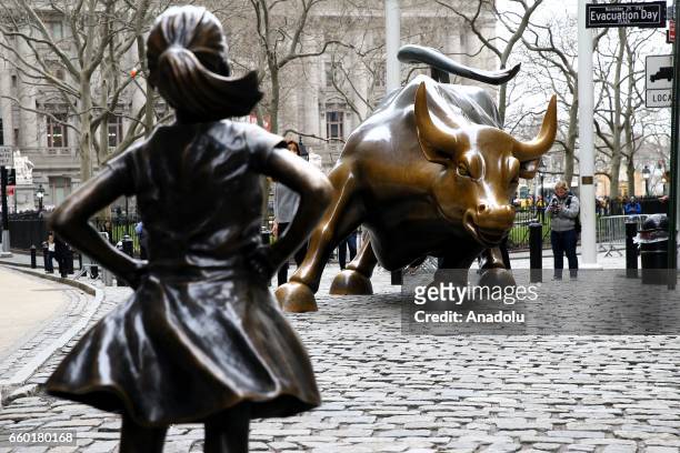 The "Fearless Girl" statue, a four-foot statue of a young girl, defiantly looks up the iconic Wall Street "Charging Bull" sculpture in New York City,...