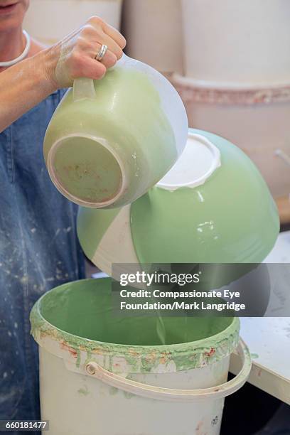 close up of woman pouring glaze over pot in studio - glazen pot stock pictures, royalty-free photos & images