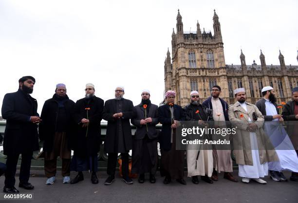 Imams hold flowers as they gather on Westminster Bridge ahead of a vigil to remember the victims of last week's Westminster terrorist attack on March...