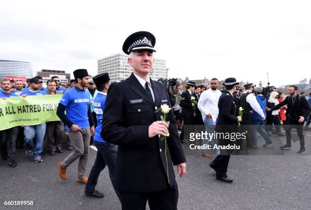 Police officers and people hold flowers as they attend a vigil to remember the victims of last week's Westminster terrorist attack on March 29, 2017...