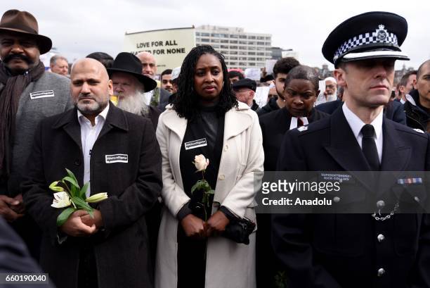 Police officers and people hold flowers as they attend a vigil to remember the victims of last week's Westminster terrorist attack on March 29, 2017...