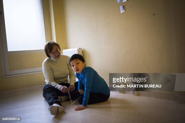 An assistant takes care of Jules, a 8-year-old autistic boy, on March 24, 2017 in Courbevoie, north-west of Paris, at the Lud'Eveil center for...