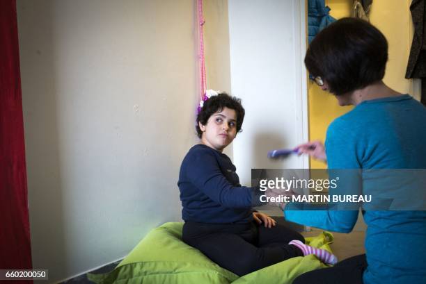Volunteer plays with Lena, a 8-year-old autistic child, on March 24, 2017 in Courbevoie, north-west of Paris, at the Lud'Eveil center for children...
