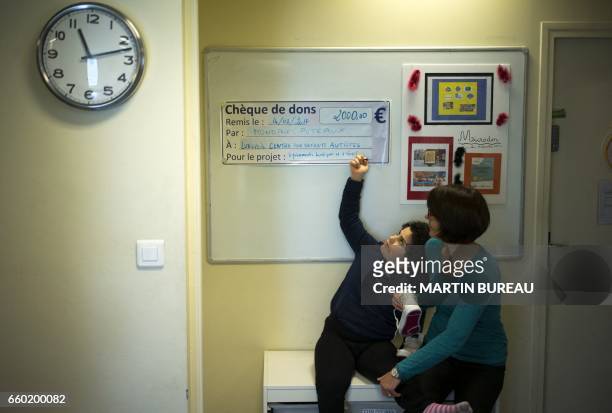 Volunteer plays with Lena, a 8-year-old autistic child, on March 24, 2017 in Courbevoie, north-west of Paris, at the Lud'Eveil center for children...